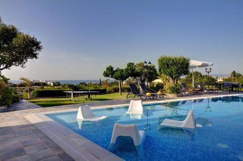 een zwembad met witte stoelen en een tafel bij Nasia Villa in Polis Chrysochous