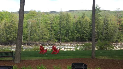 two red chairs sitting on the grass near a river at Lovely Townhouse with Views in Lincoln