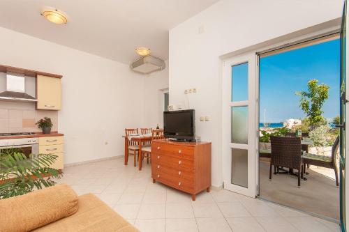a living room with a television and a table with chairs at Apartments Ruzmarin in Lun