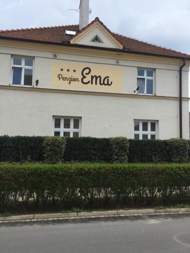 a white building with a sign on the side of it at Penzion Ema B&B in Prostějov