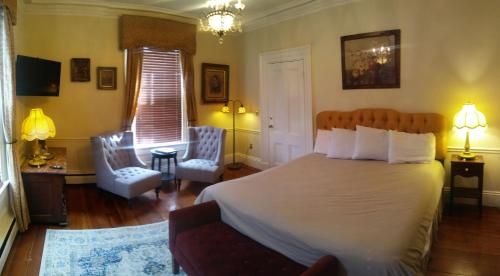 a bedroom with a large bed and a living room at Inn on Bellevue in Newport