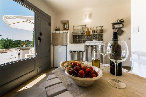 a kitchen with a table with a bowl of fruit and a wine glass at Trullo Picchiagiuda in Ostuni