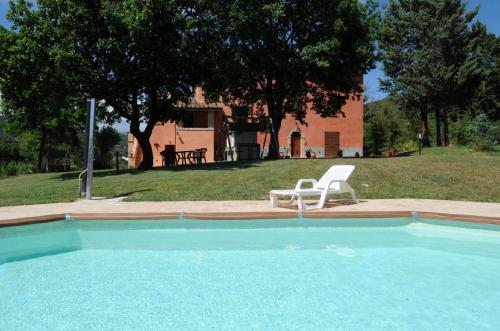 una piscina con una silla blanca y una mesa en La Carpinella, en Montone