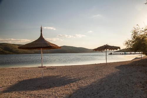 two straw umbrellas on a beach near the water at Apartment Punta in Seget Vranjica