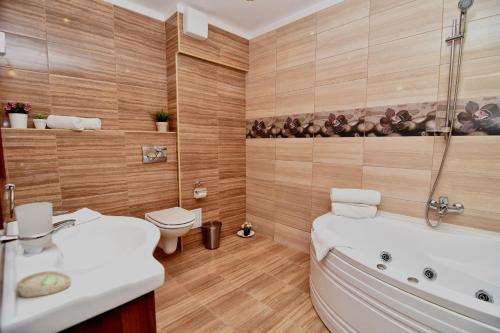 a bathroom with a tub and a toilet and a sink at Boutique Vila White Duchess in Mamaia Nord