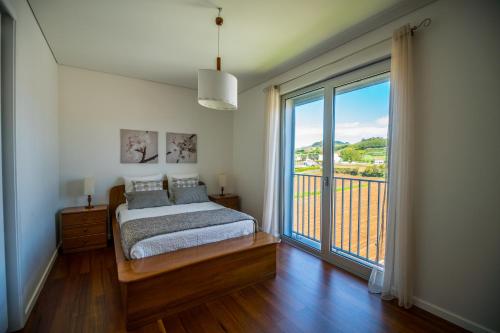 um quarto com uma cama e uma grande janela em Home at Azores - City View Apartment em Ponta Delgada
