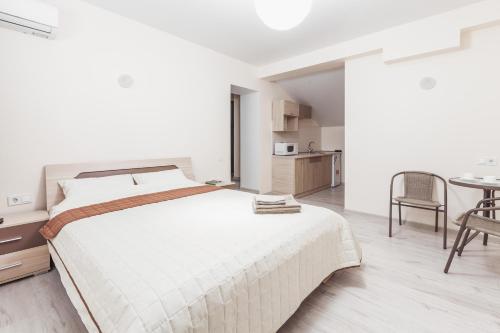 a white bedroom with a large bed and a table at Apartments near Deribasovskaya in Odesa