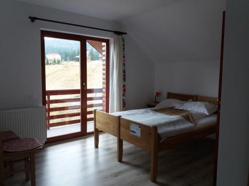 a bedroom with a bed and a large window at Pensiunea Agroturistica Alexandra in Smida