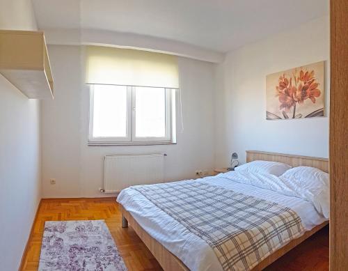 a white bedroom with a bed and a window at Apartment 31 in Pristina