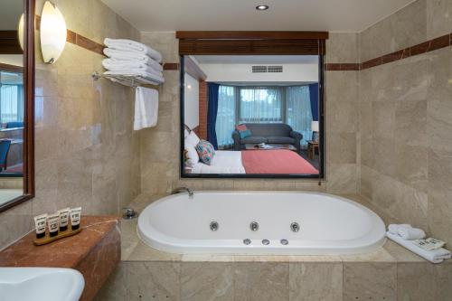 een badkamer met een bad en een grote spiegel bij Arkaba Hotel in Adelaide