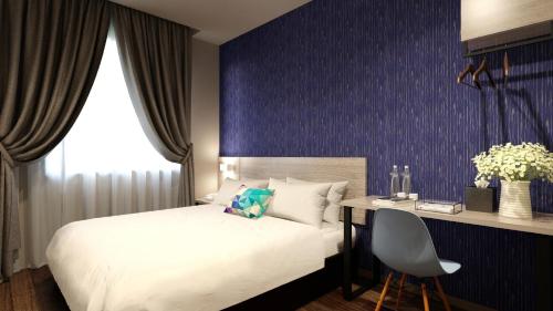 a bedroom with a bed and a desk with a chair at The Square Hotel in Skudai