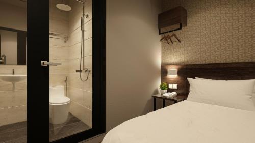 a bedroom with a bed and a bathroom with a shower at The Square Hotel in Skudai