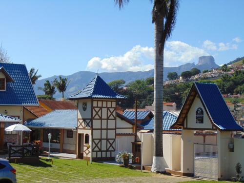 a house with a blue roof and a palm tree at Pousada Villa Da Montanha in São Bento do Sapucaí