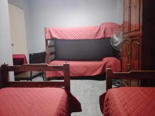 a room with three bunk beds with red sheets at Hostal Namaste in Salta
