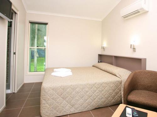 a hotel room with a bed and a chair at NRMA Cairns Holiday Park in Cairns