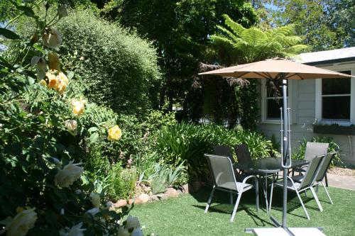 a table and chairs and an umbrella in a garden at Elm Lodge Bright in Bright