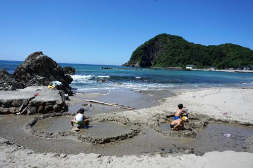 three people building a heart in the sand on a beach at Morizuya in Toyooka