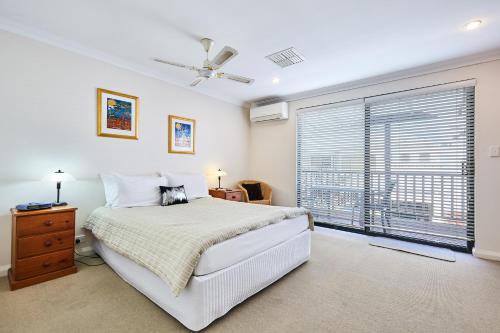 sypialnia z łóżkiem i dużym oknem w obiekcie Fremantle Townhouse Unit 6 w mieście Fremantle