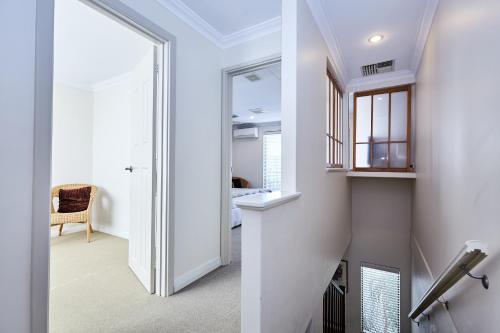 a hallway with white walls and a stairway with a mirror at Fremantle Townhouse Unit 6 in Fremantle
