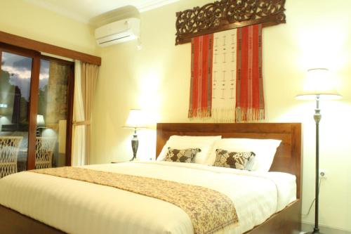 Doremi Ubud Guesthouse في أوبود: غرفة نوم بسرير كبير ومصباحين