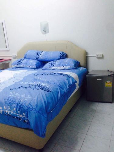 a bedroom with a bed with blue sheets and pillows at Happy Home Guest House in Ban Phe