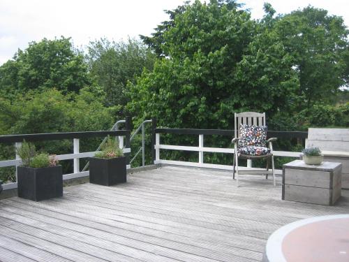 a wooden deck with a chair and two potted plants at Hotel De Waag in Bergen
