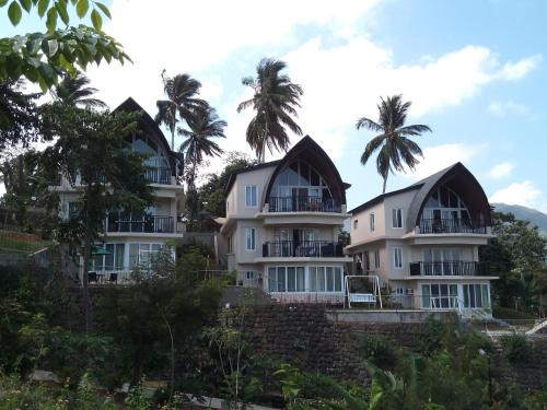a row of houses with palm trees in the background at The Duyan House at Sinagtala Resort in Orani