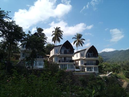 a building with two domed roofs with palm trees at The Duyan House at Sinagtala Resort in Orani