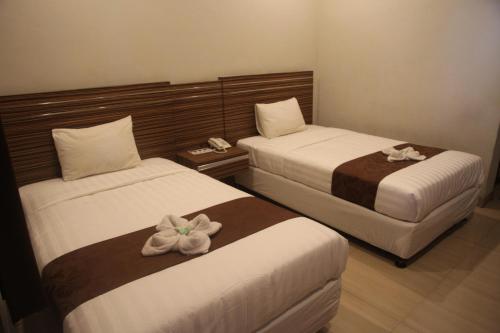 two beds in a hotel room with flowers on them at Palapa Hotel in Mataram