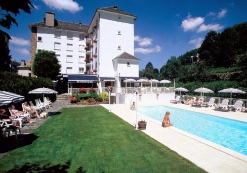 een hotel met een zwembad en een groot gebouw bij Hôtel Beauséjour in Chaudes-Aigues