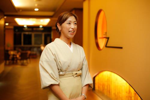 a woman is standing next to a wall at Kakimotoya in Sango