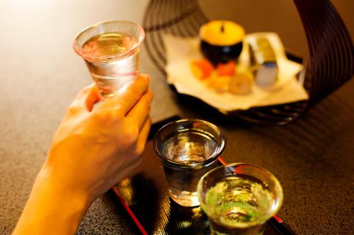 a person holding a glass of water on a table at Kakimotoya in Sango
