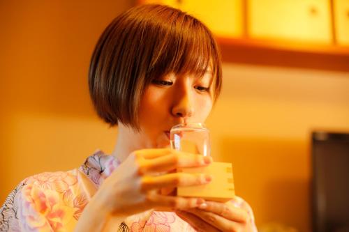 a woman drinking from a glass in a room at Kakimotoya in Sango