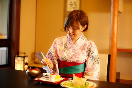 a woman sitting at a table eating food with chopsticks at Kakimotoya in Sango