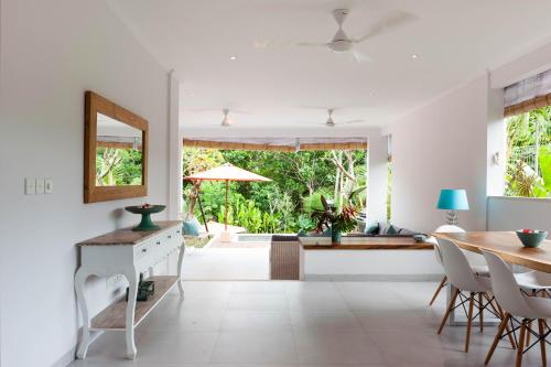 a dining room with a table and a mirror at Silversand Villa in Tanah Lot