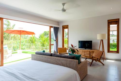 a bedroom with a bed and a couch and a television at Silversand Villa in Tanah Lot
