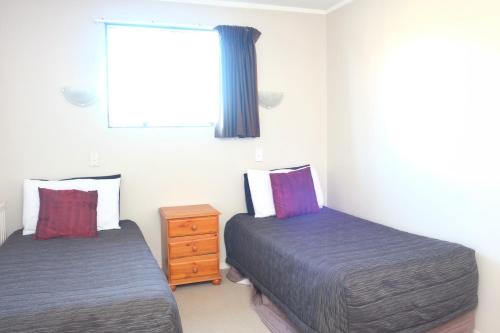 a bedroom with two beds and a window and a dresser at Gateway International Motel in Rotorua