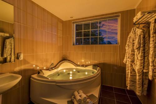 a bathroom with a tub and a sink and a window at Jubilee Chalet in Seogwipo