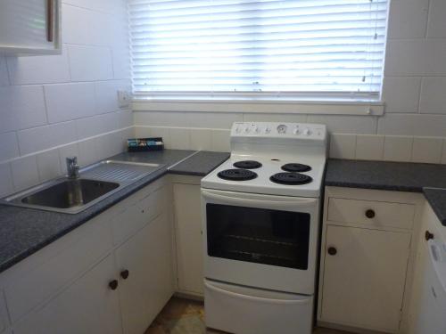 a kitchen with a white stove and a sink at Fernleaf Motel in Rotorua