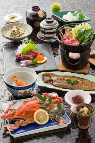 a table with plates of seafood and vegetables on it at Ryokan Seifuso in Ōmuta