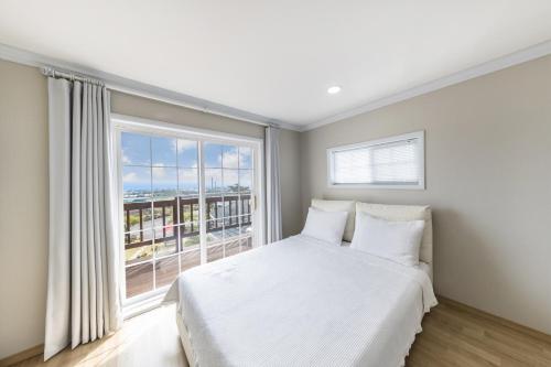 a bedroom with a white bed and a large window at Jubilee Chalet in Seogwipo
