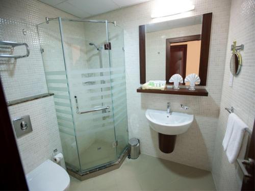 a bathroom with a glass shower and a sink at Xclusive Maples Hotel Apartment in Dubai