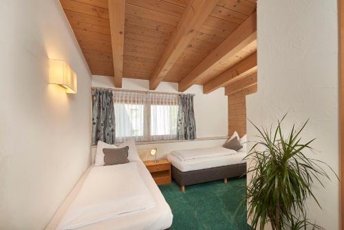 a room with two beds and a couch and a window at Landhaus Zirmhof in Saalbach Hinterglemm