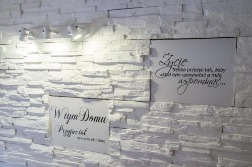 a white brick wall with two signs on it at Gościniec Pod Lipą in Mikołajki