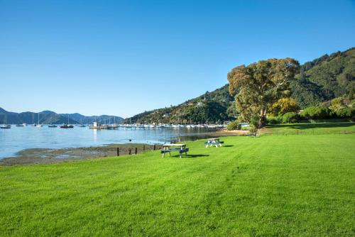 two picnic tables in a field next to the water at Bay Vista Waterfront Motel in Picton