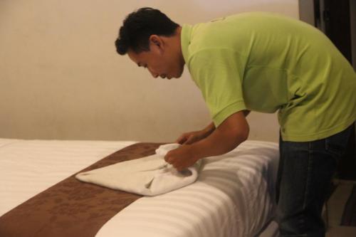 a man putting a towel on top of a bed at Palapa Hotel in Mataram