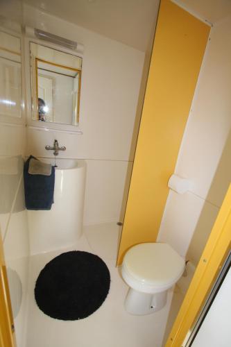 a bathroom with a white toilet and a black rug at Camping du Villard in Thorame-Basse
