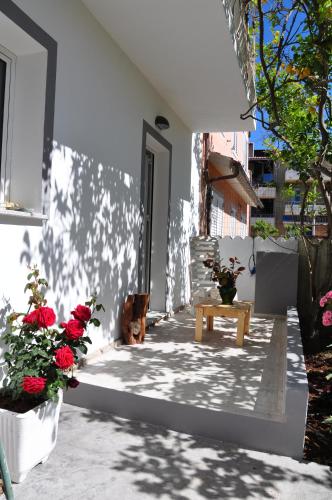 a patio with red flowers and a wooden bench at B&B Les Chambres Rooms & Suite in Santa Teresa Gallura