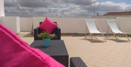 a patio with two chairs and a couch with a pink pillow at Casa Maria Victoria in Beja