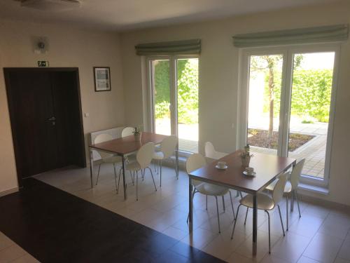 a dining room with two tables and chairs and windows at Penzion Hermina in Veselí nad Moravou